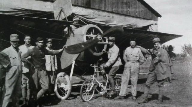 Piloti e avieri della Prima guerra mondiale in posa davanti a un caccia, accanto a un hangar